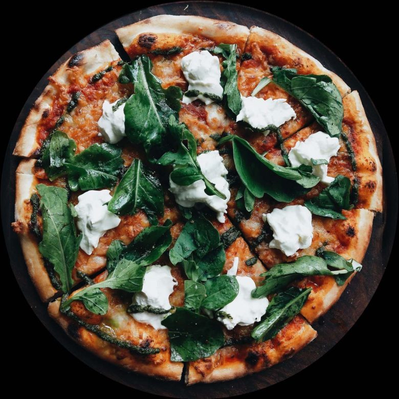 A pizza topped with spinach and feta cheese.